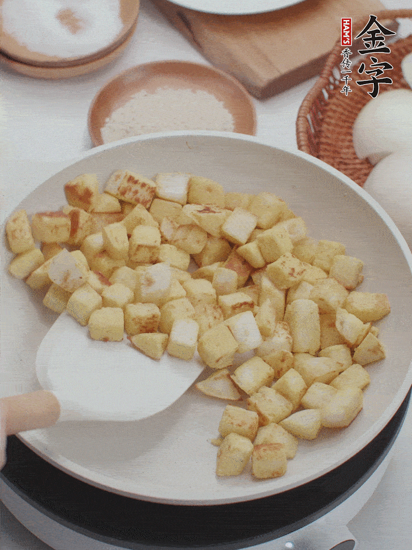 起鍋熱油，倒入饅頭丁，小火煎至蛋液凝固定型再翻面，饅頭丁部煎至金黃時盛起待用。