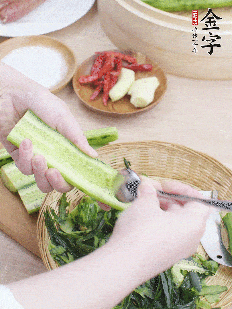 黃瓜削皮，對半切開，勺子挖去內(nèi)瓤，斜刀切片。青蒜斜刀切段。
