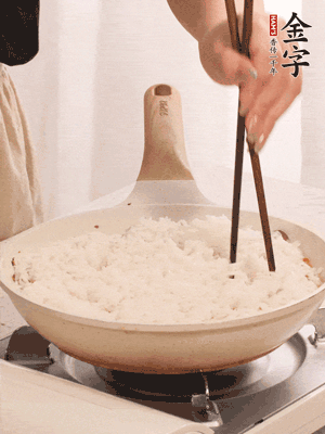 把瀝干水分的米飯均勻鋪在上面，筷子戳幾個(gè)洞，以便透氣，轉(zhuǎn)小火蓋上蓋子燜至水分收干，大概10分鐘。